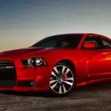 Czerwony Dodge Charger 5.7 Hemi SRT lśni w zachodzącym słońcu, gotowy do jazdy po pustynnej drodze.