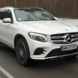 Biały Mercedes GLC 220d z czarnym dachem jedzie po drodze, otoczony zimowym krajobrazem.