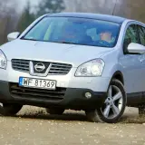 Srebrny Nissan Qashqai 1.6 benzyna pokonuje nierówności na drodze gruntowej, unosząc kurz spod kół.