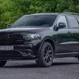 Czarny Dodge Durango 3.6, lśniący na tle zieleni. Potężny SUV gotowy na każdą podróż.