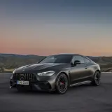 Mroczny Mercedes-AMG GT Coupe na tle zachodzącego słońca i pagórków.