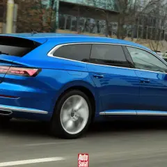 Błękitny Volkswagen Arteon Shooting Brake w ruchu ulicznym. Elegancka linia nadwozia i sportowe felgi podkreślają jego dynamiczny charakter.