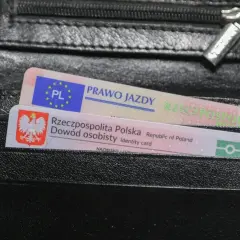 Czarny portfel z polskim dowodem osobistym i prawem jazdy. Na dokumencie prawa jazdy widnieje napis "PRAWO JAZDY", a na dowodzie "Rzeczpospolita Polska Dowód osobisty".