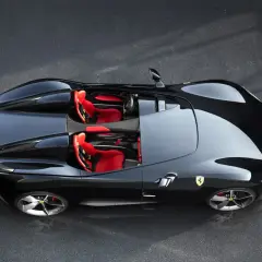 Czarny Ferrari Monza SP2 z czerwonymi siedzeniami, gotowy do jazdy po torze.