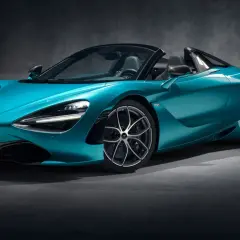 Turkusowy McLaren 720S Spider z otwartym dachem, gotowy do jazdy po torze.