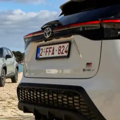 Dwa samochody Toyota, jeden biały, drugi zielony, stoją nad wodą. To świetny przykład, czym jest crossover – wszechstronny pojazd na każdą okazję.