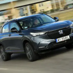 Ciemnoszary Honda HR-V jedzie po drodze, widok z przodu i z boku.