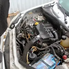 Silnik renault kangoo 1.5 dci z widocznym akumulatorem i przewodami. W tle śnieg na masce i szybie.
