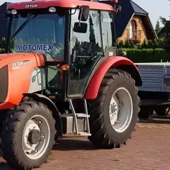 Czerwony Zetor z przyczepą, gotowy do pracy. Posiadanie prawa jazdy na traktor otwiera drogę do wielu możliwości.
