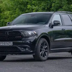 Czarny Dodge Durango 3.6, lśniący na tle zieleni. Potężny SUV gotowy na każdą podróż.
