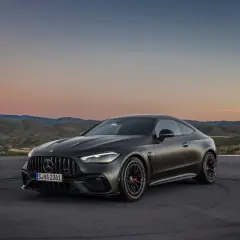 Mroczny Mercedes-AMG GT Coupe na tle zachodzącego słońca i pagórków.