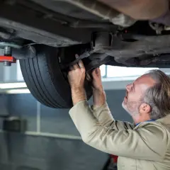 Mechanik sprawdza podwozie samochodu i koło.