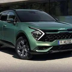 Nowy zielony Kia Sportage 1.6 benzyna prezentuje się nowocześnie przed budynkiem.