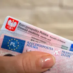 Dłoń trzyma polski dowód osobisty i prawo jazdy. To ważne dokumenty, które pozwalają na swobodne podróżowanie, a prawo jazdy bezterminowe daje spokój na lata.