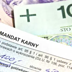Mandat karny z kwotą 100 zł na tle polskich banknotów.