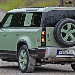 Zielony Land Rover Defender na szutrowej drodze, gotowy na przygodę.
