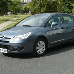 Szary Citroen C4 1.6 HDI zaparkowany na tle parku.