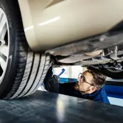 Mechanik z latarką bada podwozie samochodu.