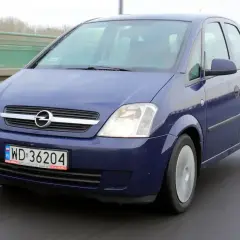 Niebieski Opel Meriva 1.6 benzyna jedzie po mokrej drodze.