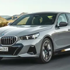 Szare BMW 540d jedzie po drodze na tle górskiego krajobrazu.