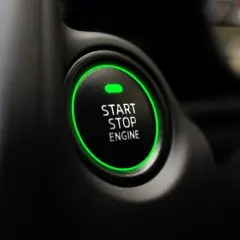 Przycisk "START STOP ENGINE" z zieloną obwódką, gotowy do odpalenia auta.