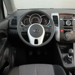 Wnętrze Kia Venga 1.4 benzyna: kierownica z logo Kia, deska rozdzielcza z radiem i nawiewami, dźwignia zmiany biegów.