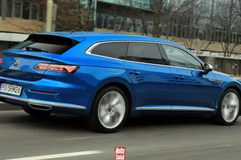 Błękitny Volkswagen Arteon Shooting Brake w ruchu ulicznym. Elegancka linia nadwozia i sportowe felgi podkreślają jego dynamiczny charakter.