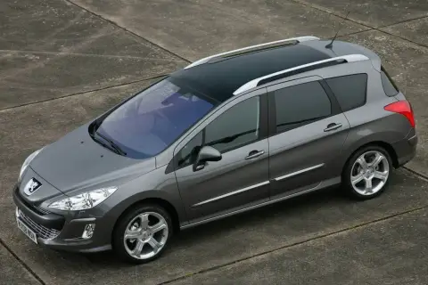 Szary Peugeot 308 1.6 HDi kombi z panoramicznym dachem stoi na betonowej nawierzchni.