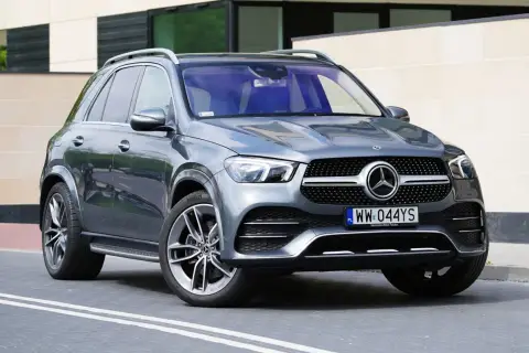 Szary Mercedes GLE 300d z eleganckimi felgami stoi przed nowoczesnym budynkiem.