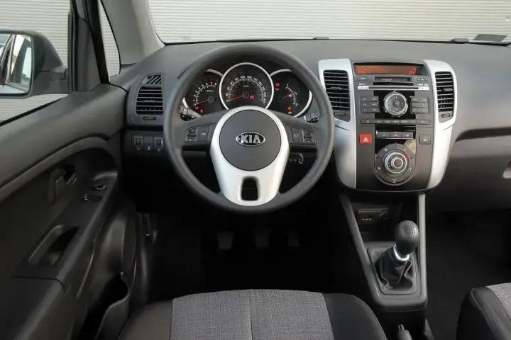 Wnętrze Kia Venga 1.4 benzyna: kierownica z logo Kia, deska rozdzielcza z radiem i nawiewami, dźwignia zmiany biegów.