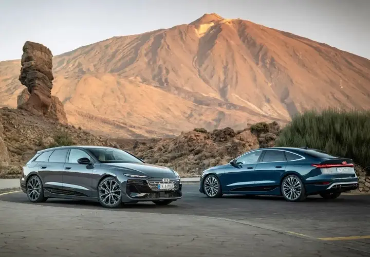 Dwa lśniące Audi, jeden sedan, drugi kombi, na tle majestatycznej góry.
