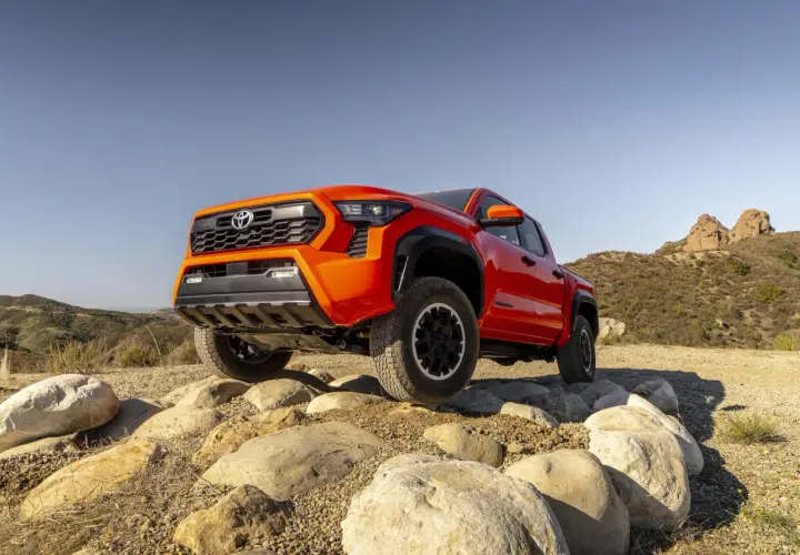 Pomarańczowa Toyota Tacoma pokonuje skalisty teren.