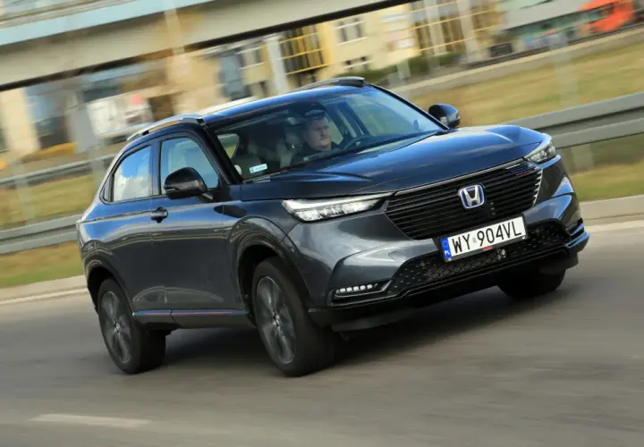 Ciemnoszary Honda HR-V jedzie po drodze, widok z przodu i z boku.