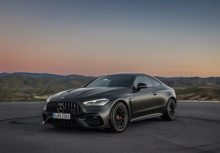 Mroczny Mercedes-AMG GT Coupe na tle zachodzącego słońca i pagórków.