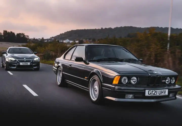 Klasyczne bmw 635 csi i nowszy model jadą drogą o zachodzie słońca.