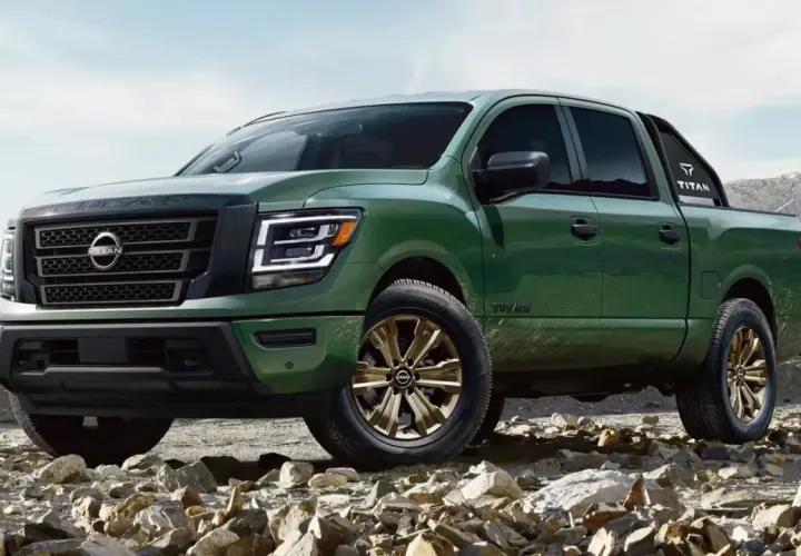 Zielony Nissan Titan z brązowymi felgami na kamienistym podłożu, gotowy na przygodę w górach.