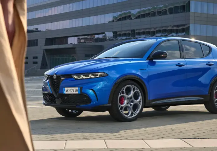 Niebieskie Alfa Romeo Tonale błyszczy na tle nowoczesnego budynku. Sprawdź aktualną alfa romeo tonale cena i odkryj jego możliwości.