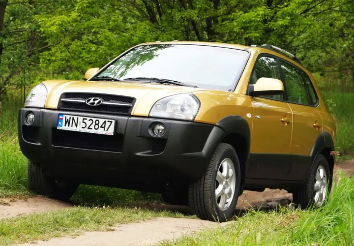 Złoty Hyundai Tucson 2007 na leśnej drodze, gotowy na przygodę.
