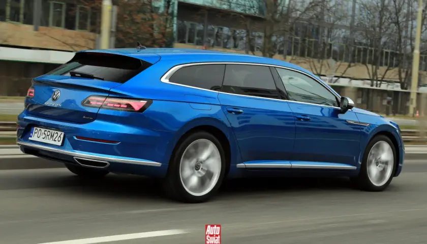 Błękitny Volkswagen Arteon Shooting Brake w ruchu ulicznym. Elegancka linia nadwozia i sportowe felgi podkreślają jego dynamiczny charakter.