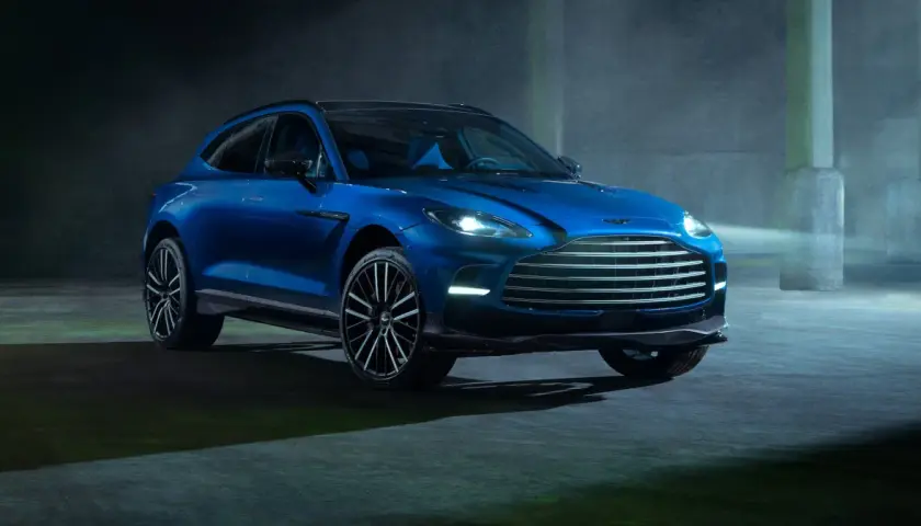 Niebieski Aston Martin DBX 707 lśni w półmroku, gotowy do podboju każdej drogi.