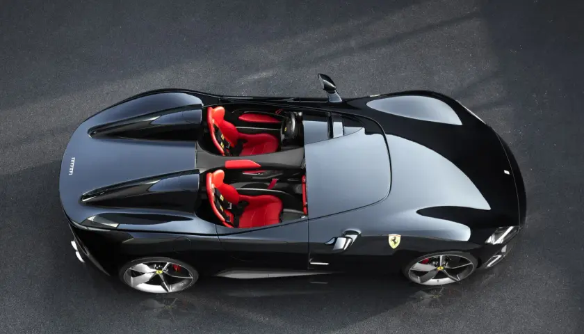 Czarny Ferrari Monza SP2 z czerwonymi siedzeniami, gotowy do jazdy po torze.