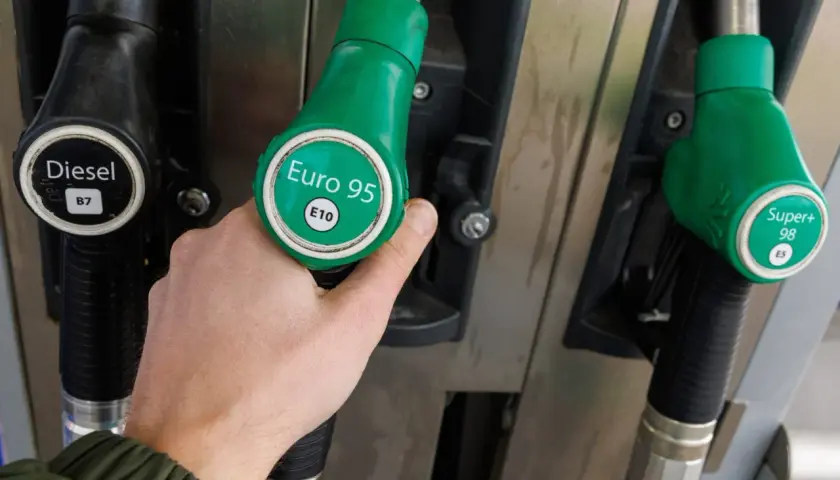 Dłoń trzyma zielony pistolet do tankowania z napisem "Euro 95 E10". Obok widać pistolet do diesla. Czas na tankowanie benzyny!