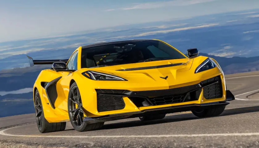 Żółty Chevrolet Corvette C8 z dużym tylnym skrzydłem na górskiej drodze.