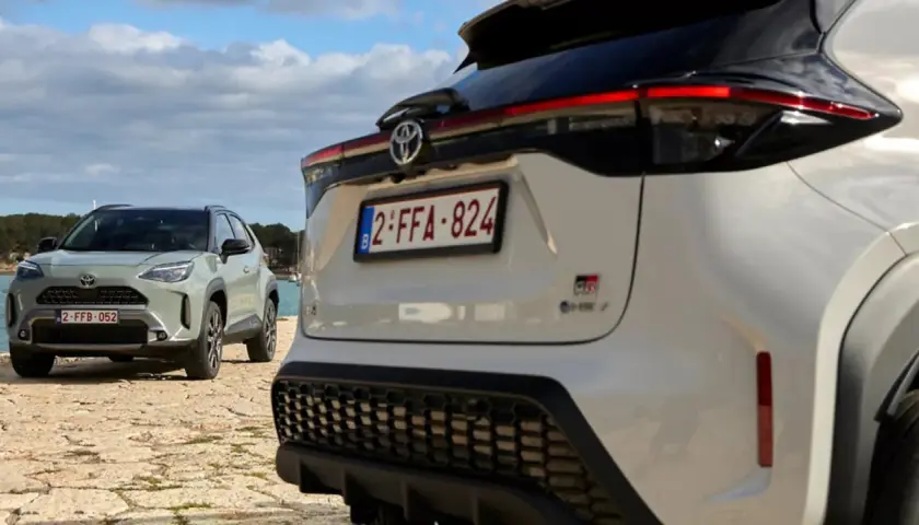Dwa samochody Toyota, jeden biały, drugi zielony, stoją nad wodą. To świetny przykład, czym jest crossover – wszechstronny pojazd na każdą okazję.