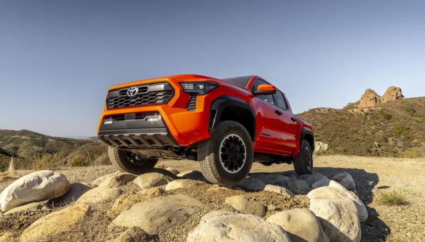 Pomarańczowa Toyota Tacoma pokonuje skalisty teren.