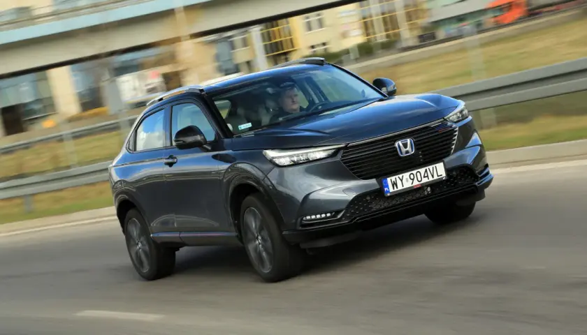 Ciemnoszary Honda HR-V jedzie po drodze, widok z przodu i z boku.