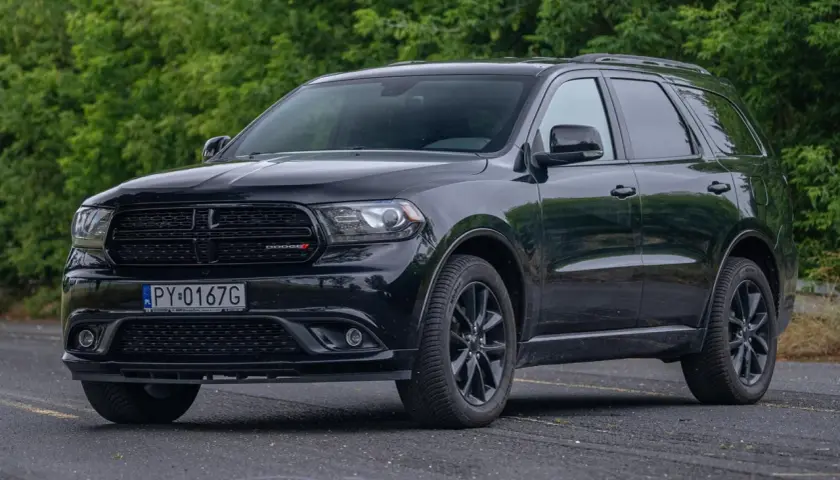 Czarny Dodge Durango 3.6, lśniący na tle zieleni. Potężny SUV gotowy na każdą podróż.