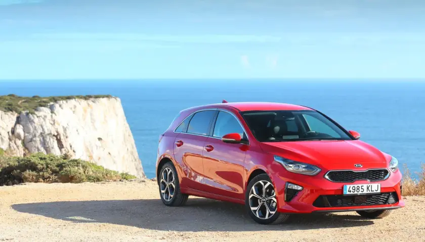 Czerwona Kia Ceed 1.4 benzyna na tle klifu i morza. Idealna na wakacyjne podróże.