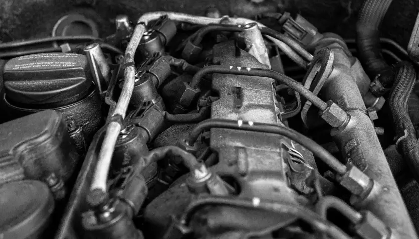 Widok silnika samochodowego. Na korku widać napis "To avoid damage to engine oil must not exceed max", sugerujący, że jest za dużo oleju w silniku.