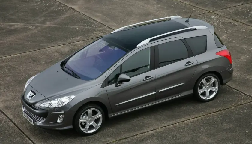 Szary Peugeot 308 1.6 HDi kombi z panoramicznym dachem stoi na betonowej nawierzchni.